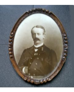 Portretfoto van een marineofficier in ovale notenhouten lijst, ca. 1900